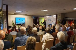 Groep bewoners tijdens een informatieavond over klimaatadaptatie, georganiseerd door de gemeente Best en Raintanks, zittend in een zaal terwijl ze luisteren naar een presentatie over de voordelen van collectief inkopen voor klimaatbestendige oplossingen.