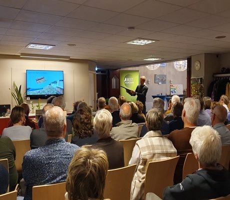 Groep bewoners tijdens een informatieavond over klimaatadaptatie, georganiseerd door de gemeente Best en Raintanks, zittend in een zaal terwijl ze luisteren naar een presentatie over de voordelen van collectief inkopen voor klimaatbestendige oplossingen.